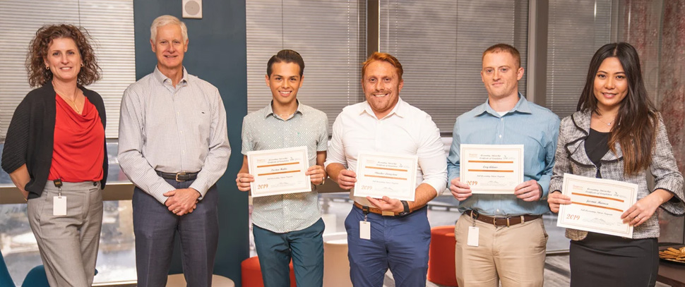 Four account interns holding their certificates: Cory Adams, Preston Halla, Jasmin Maruca and Phinehas Livingston.