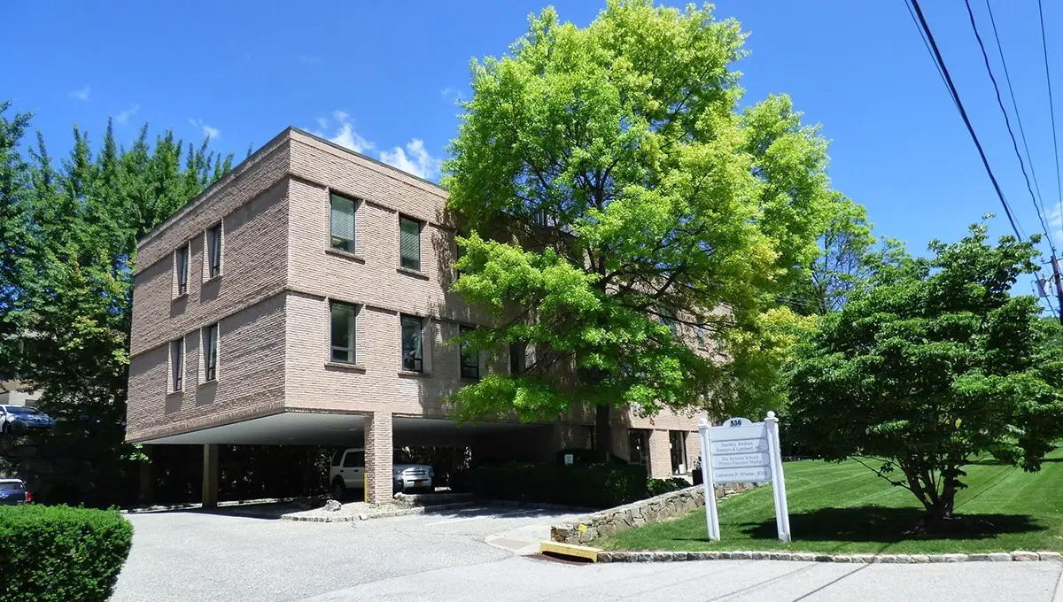 A three level office complex surrounded by lush, green trees and foliage