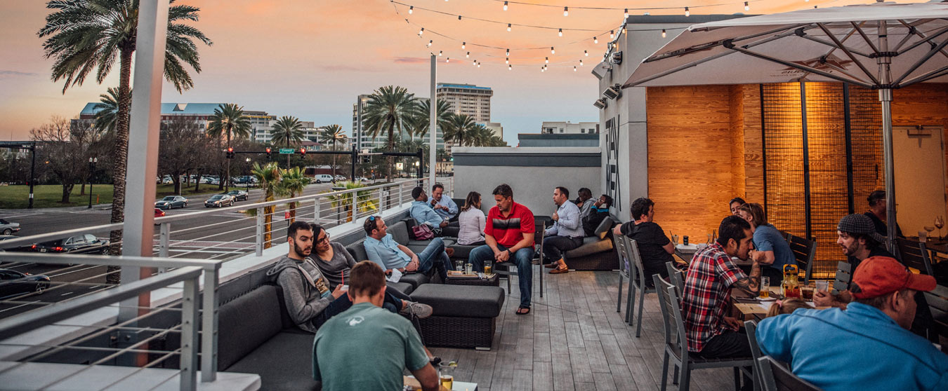 Groups of people eating and having beverages on a rooftop patio.