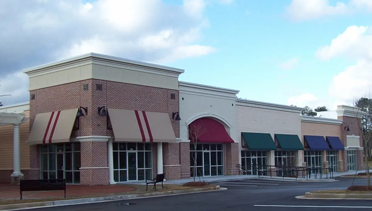 A line of shopping units with windows, doors and awnings visible.