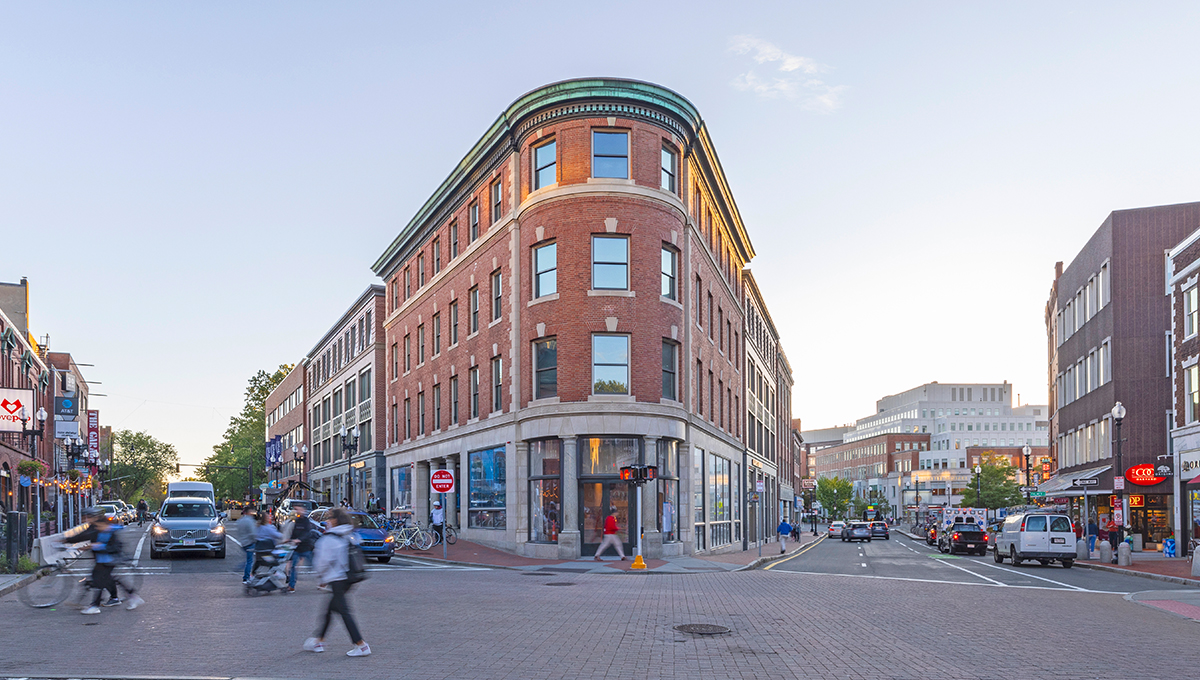 A street level view of the distinctive rounded corner of The Abbot Building in a busy downtown street.