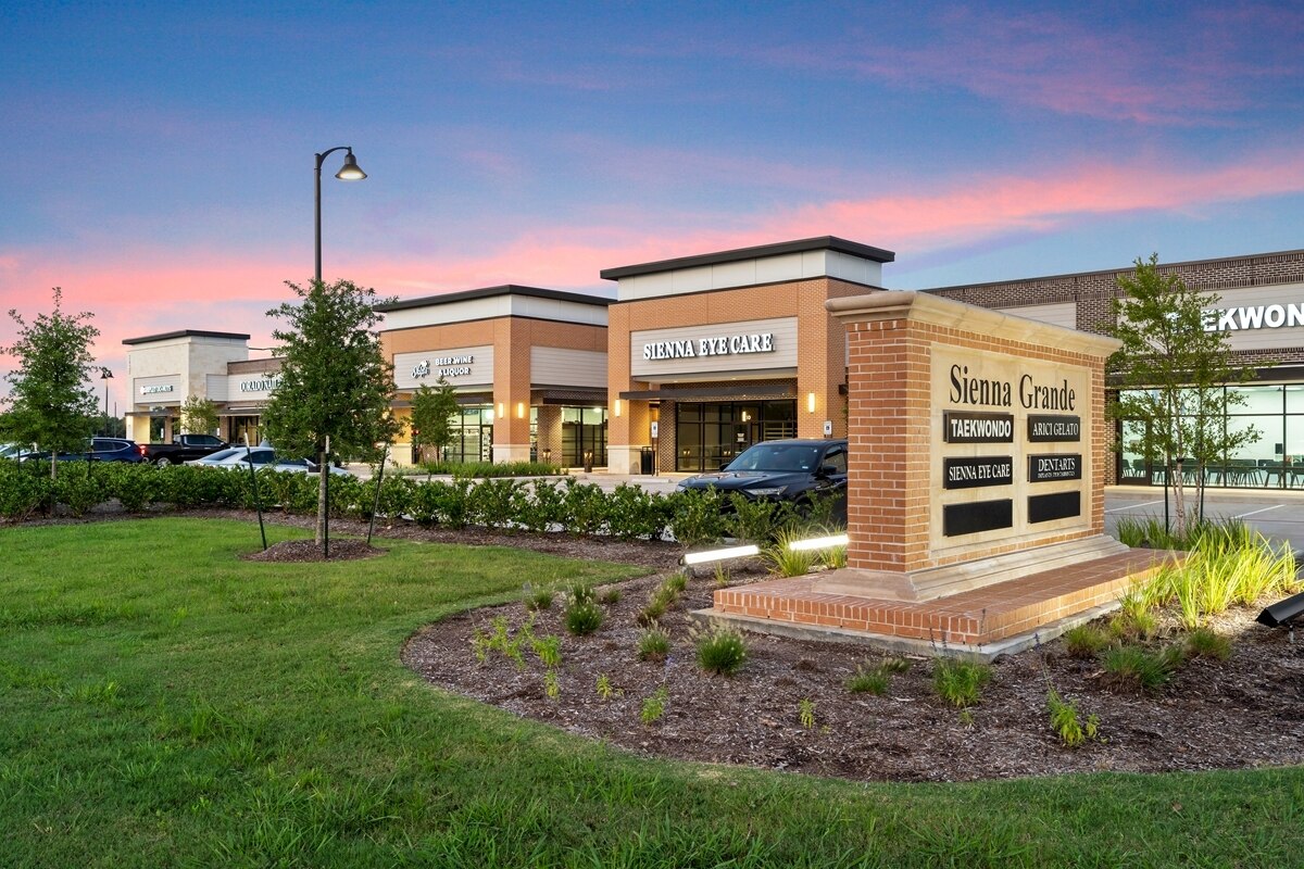 Sienna Grande Shops, featuring local retailers and a monument sign with retailer names.